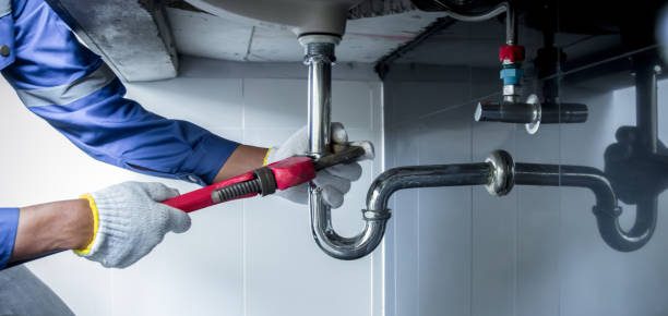 Plumber tightening a leaking waste trap with a pipe wrench